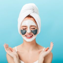 front-view-woman-doing-spa-treatment-with-closed-eyes-studio-shot-charming-girl-with-face-mask-standing-blue-background(1)